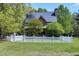 Charming brick home featuring a well-manicured lawn, white picket fence, and lush greenery at 8120 Stillbreeze Dr, Fuquay Varina, NC 27526