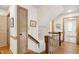 Hallway with hardwood floors, beige doors, a staircase with wood banister, and access to laundry room at 8120 Stillbreeze Dr, Fuquay Varina, NC 27526