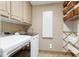 Bright laundry room featuring cabinets, washer, dryer, folding rack, and storage space with wicker baskets on shelves at 8120 Stillbreeze Dr, Fuquay Varina, NC 27526