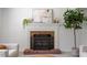 Close-up view of the decorative brick fireplace with an iron grate and plants on the mantle at 904 Emory Ln, Raleigh, NC 27609