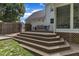 Wide wooden staircase leading up to deck with outdoor dining set, enclosed by fence, and adjacent to well-manicured lawn at 1005 Thorncroft Ln, Apex, NC 27502