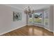 Charming dining room featuring hardwood floors, decorative chandelier, and large windows overlooking the front yard at 1005 Thorncroft Ln, Apex, NC 27502