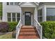 Inviting front door with brick steps, white railings, and manicured landscaping at 1005 Thorncroft Ln, Apex, NC 27502