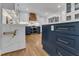 A spacious kitchen with white cabinets, a wooden vent hood, and a marble countertop island with navy blue accents at 1005 Thorncroft Ln, Apex, NC 27502