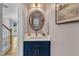 Stylish powder room with a blue vanity, marble countertop, oval mirror, and modern fixtures at 1005 Thorncroft Ln, Apex, NC 27502