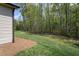 Side yard of home with healthy lawn and a wooded border of tall, green trees at 1007 Fairhaven Dr, Mebane, NC 27302