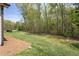 Side yard of home with a healthy lawn and wooded border of tall, green trees at 1007 Fairhaven Dr, Mebane, NC 27302