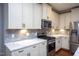 Well-lit kitchen featuring modern appliances, marble countertops, stainless steel oven, and off-white cabinetry at 1007 Fairhaven Dr, Mebane, NC 27302