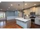 A bright open kitchen with island featuring stainless steel appliances, marble countertops, and hardwood floors at 1007 Fairhaven Dr, Mebane, NC 27302