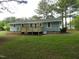 Back exterior view of a light blue home with a new wooden deck and well-maintained green lawn at 1165 John Mitchell Rd, Youngsville, NC 27596