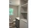 A full bathroom with a single vanity, shelving and view to the backyard at 1165 John Mitchell Rd, Youngsville, NC 27596