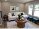 Welcoming living room with a white sofa, round wooden table, and natural light from the window at 1165 John Mitchell Rd, Youngsville, NC 27596