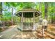 The outdoor gazebo has a table, seating, and an information stand surrounded by flowering shrubs and woods at 12 Innisfree Dr, Durham, NC 27707