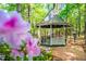 Picturesque gazebo featuring classic architecture amid a garden setting with flowering plants and a brick path at 12 Innisfree Dr, Durham, NC 27707
