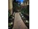 Charming brick walkway illuminated with landscape lighting, nestled between lush green bushes and a brick wall at 12 Innisfree Dr, Durham, NC 27707