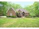 Charming brick home with lush landscaping and mature trees providing curb appeal and privacy at 14 Whit Ct, Angier, NC 27501