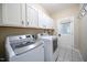 Laundry room featuring tile flooring, white cabinets and modern washer and dryer at 14 Whit Ct, Angier, NC 27501