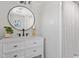 Modern bathroom with white cabinets, marble countertop, round mirror, and updated shower with rod at 1514 Goodwin Rd, Durham, NC 27712