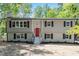 Charming home featuring a bright red front door, black shutters and surrounded by mature trees at 1514 Goodwin Rd, Durham, NC 27712