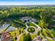 Expansive estate aerial showcasing manicured grounds, a circular driveway, a pond, and mature trees at 16 Portofino Pl, Durham, NC 27707