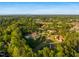 Aerial view of a private estate with a pool, pond, and beautiful grounds surrounded by trees at 16 Portofino Pl, Durham, NC 27707