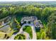 Luxury home aerial showcasing manicured grounds, swimming pool, and stately architecture amid a lush forest backdrop at 16 Portofino Pl, Durham, NC 27707