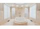 Bright bathroom with a large soaking tub between two arched shower entrances and windows at 16 Portofino Pl, Durham, NC 27707