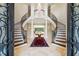 Grand foyer with dual staircase, marble floors, chandelier, and view into the living room at 16 Portofino Pl, Durham, NC 27707
