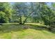 Spacious backyard with a fire pit area and views of a creek surrounded by trees at 1835 Pearidge Rd, Angier, NC 27501