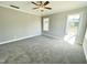 Spacious bedroom featuring plush gray carpeting, a ceiling fan, and multiple windows at 186 Gumtop Dr, Zebulon, NC 27597