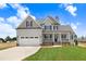 Charming two-story home with a well-manicured lawn and a two-car garage under a sunny, partly cloudy sky at 186 Gumtop Dr, Zebulon, NC 27597