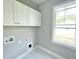 Bright laundry room with ample cabinet storage, window with natural light, and tile floors at 186 Gumtop Dr, Zebulon, NC 27597