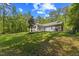 Lush backyard featuring a well-manicured lawn, mature trees, and a cozy screened-in porch with patio at 205 Sacred Fire Rd, Louisburg, NC 27549
