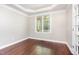 Bright bedroom featuring tray ceilings, hardwood floors, and a large window offering scenic views at 2106 Cloud Cover Ln, Raleigh, NC 27614