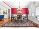 Elegant dining room with red accent wall, hardwood floors, and a decorative chandelier, creating a sophisticated ambiance at 215 Terrell Dr, Rolesville, NC 27571