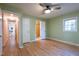 Green bedroom with hardwood floors, a ceiling fan, and two open doors leading to a bathroom and hallway at 2506 N Duke St, Durham, NC 27704