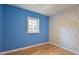 Cozy bedroom featuring colorful floral wallpaper, blue accent walls, and natural hardwood flooring at 2506 N Duke St, Durham, NC 27704