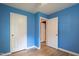 Blue bedroom has hardwood floors and two white doors, one to a closet and one to a bathroom at 2506 N Duke St, Durham, NC 27704