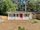 Charming home featuring a cozy front porch, red front door, solar panels, and a beautifully landscaped yard at 2506 N Duke St, Durham, NC 27704