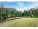 Green backyard features a gentle slope down to a small pond surrounded by trees at 2749 Nettles Ridge Way, Fuquay Varina, NC 27526