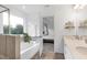 Bright bathroom featuring a soaking tub, double vanity, and an open doorway to the main bedroom at 2749 Nettles Ridge Way, Fuquay Varina, NC 27526