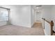 Upstairs hallway with neutral carpet, white walls, white doors, and a staircase with white railings at 2749 Nettles Ridge Way, Fuquay Varina, NC 27526