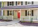 Up close view of a charming front porch with classic white railings, a red front door, and black shutters at 2806 Shaftsbury St, Durham, NC 27704