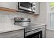 Modern kitchen features stainless steel stove and microwave with gray tile backsplash at 2806 Shaftsbury St, Durham, NC 27704
