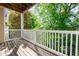 Private balcony with wooden floor and white railing surrounded by lush trees at 2810 Bedford Green Dr # 207, Raleigh, NC 27604