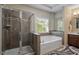 Bathroom featuring a glass shower, soaking tub, and decorative tile accents at 3009 Weston Green Loop, Cary, NC 27513