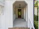 Covered porch with brick and concrete flooring and a wood framed front door at 3316 Milton Rd, Raleigh, NC 27609