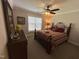 Cozy bedroom with ceiling fan, double window, and a neatly made wrought iron queen bed with red striped bedding at 4103 Cheek Point Pl, Burlington, NC 27215