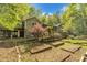 View of a home with multiple decks and raised garden beds, surrounded by beautiful trees under a partially cloudy sky at 480 Big Branch Dr, Pittsboro, NC 27312