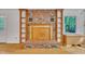 Close-up of a brick fireplace with wood mantle, built-in shelving, and views of the backyard, creating a cozy focal point at 480 Big Branch Dr, Pittsboro, NC 27312